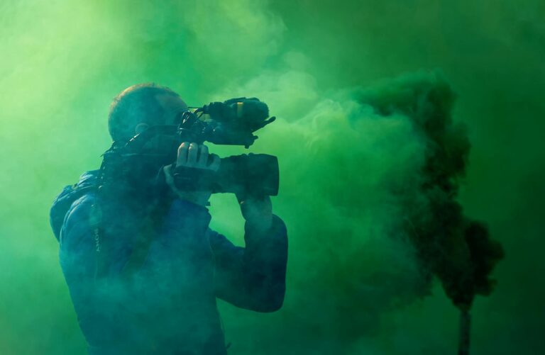 A professional cameraman captures footage surrounded by striking green smoke, highlighting filmmaking elements.